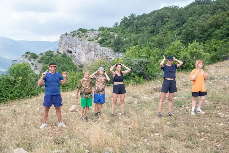 Туристы делают зарядку перед дневным переходом по горам Крыма